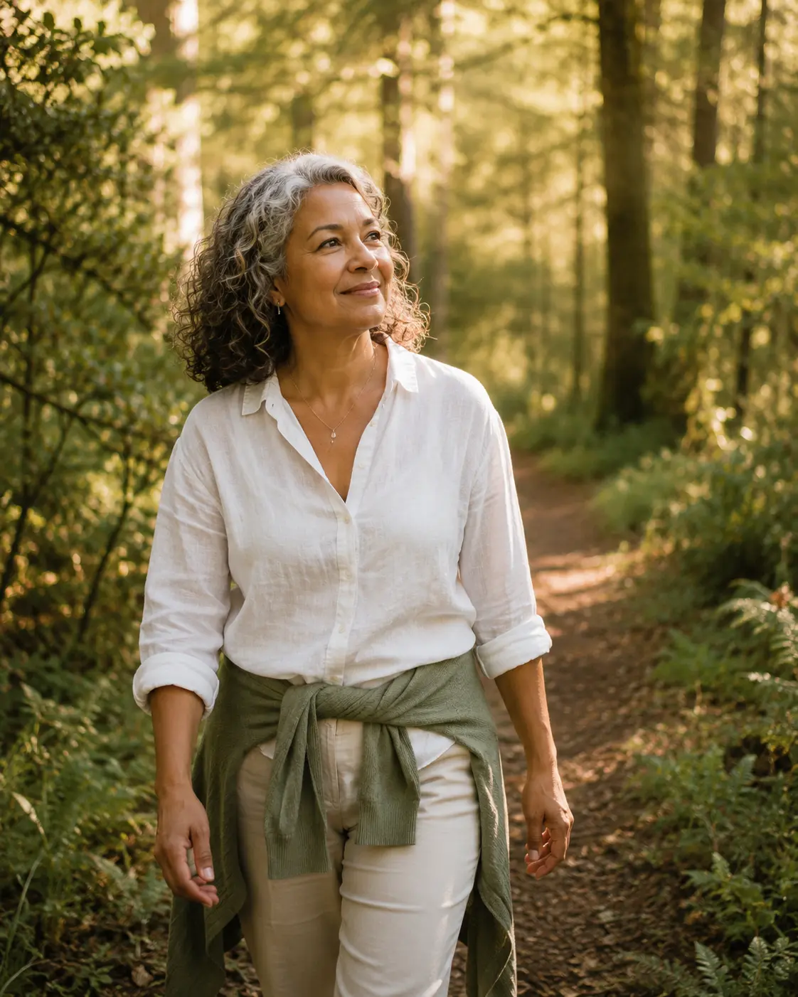 A woman walking peacefully along a sunlit forest trail